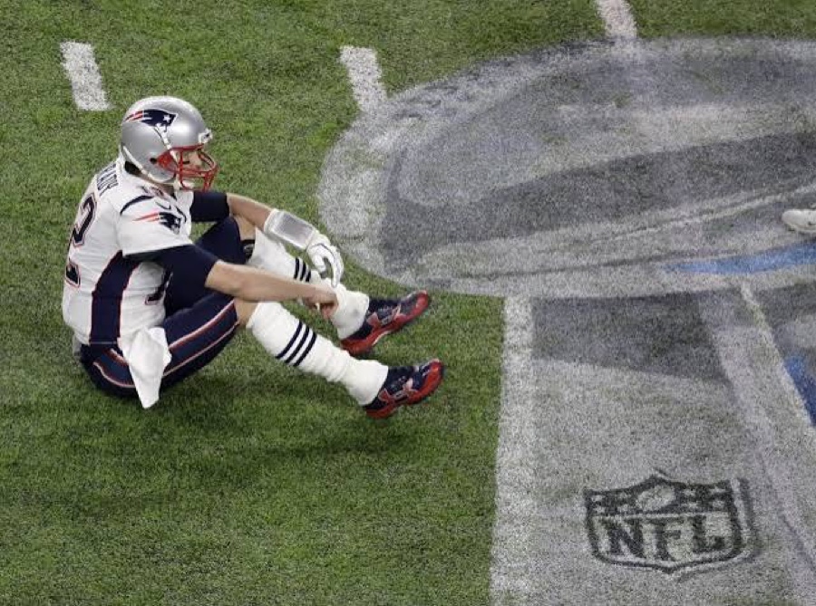 Quarterback sitting on the field, composed after a tough moment in the game